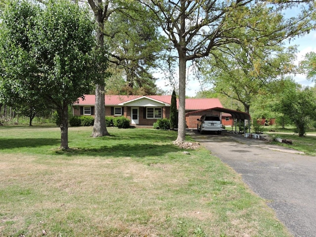 ranch-style home featuring a front lawn, driveway, a detached carport, and metal roof