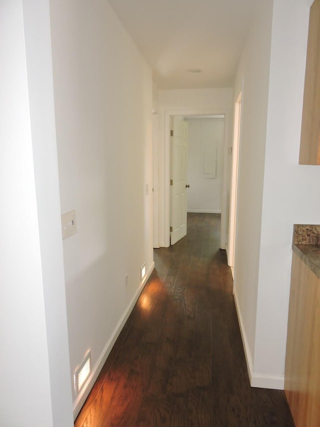 hallway featuring baseboards, hardwood / wood-style floors, and visible vents