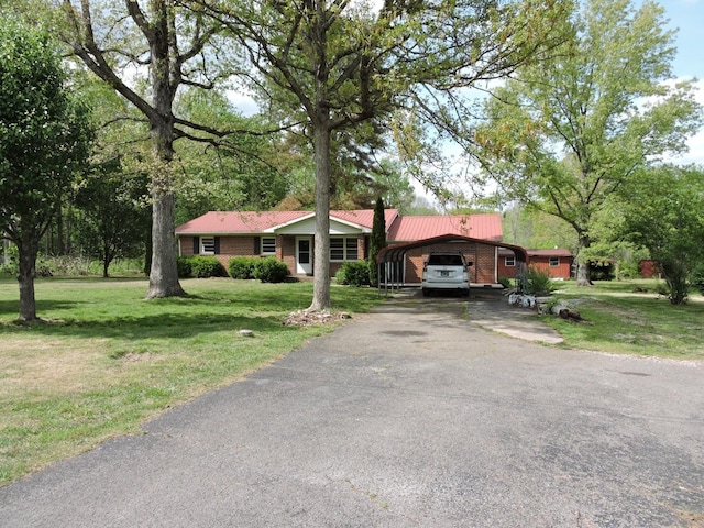 ranch-style home featuring a carport, metal roof, brick siding, a front yard, and aphalt driveway