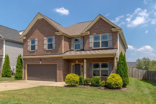 craftsman house featuring concrete driveway, an attached garage, fence, a front yard, and brick siding
