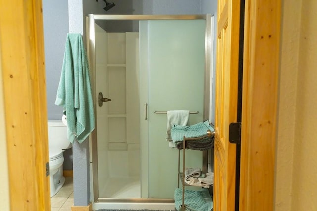 full bathroom with toilet, tile patterned floors, and a shower stall