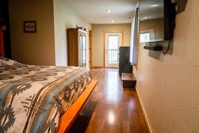 bedroom featuring baseboards, a textured wall, recessed lighting, and wood finished floors