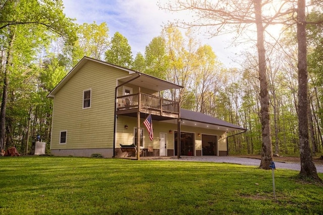 rear view of property featuring a lawn, an attached garage, and driveway