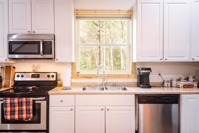 kitchen with a sink, appliances with stainless steel finishes, white cabinetry, and light countertops