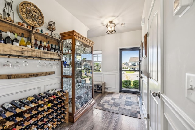 wine cellar featuring wood finished floors, a decorative wall, and a wainscoted wall