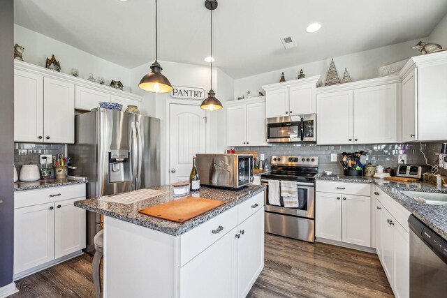 kitchen with a center island, decorative backsplash, stainless steel appliances, white cabinets, and visible vents