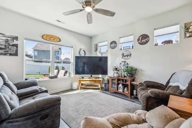 living area featuring ceiling fan, baseboards, a healthy amount of sunlight, and visible vents