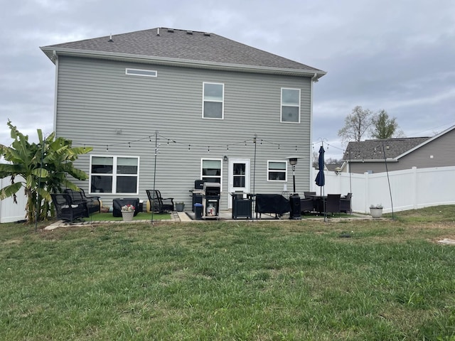rear view of property featuring fence, outdoor lounge area, a lawn, a shingled roof, and a patio