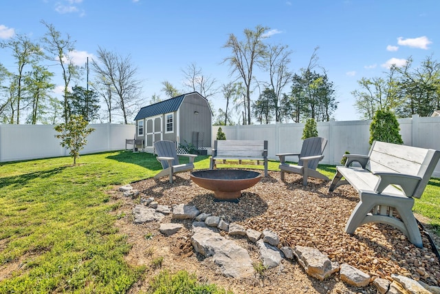 view of yard featuring a fenced backyard, an outbuilding, a fire pit, and a shed