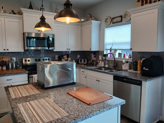 kitchen featuring backsplash, appliances with stainless steel finishes, a sink, and white cabinetry