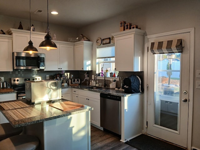kitchen featuring white cabinets, backsplash, appliances with stainless steel finishes, and a sink