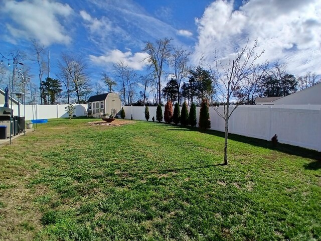 view of yard featuring a fenced backyard, an outdoor structure, and a storage shed