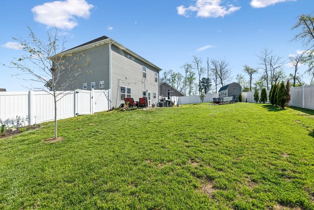 view of yard with a fenced backyard, a gate, an outbuilding, and a storage unit