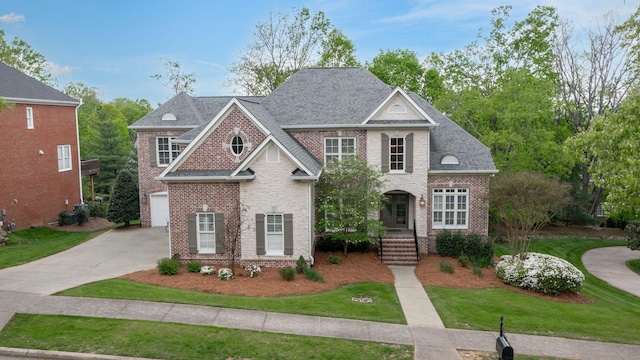traditional-style home featuring a front lawn, driveway, brick siding, and a garage