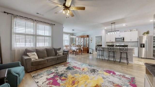 living area with ceiling fan, light wood-style floors, and recessed lighting