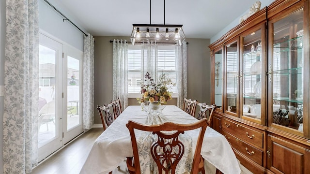 dining space with healthy amount of natural light, a chandelier, and light wood-type flooring