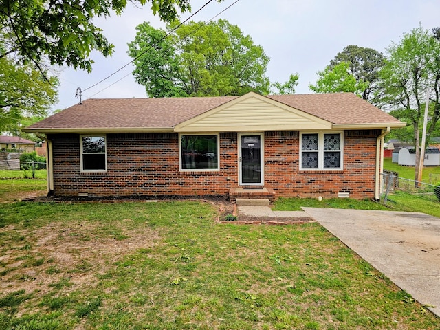 single story home with brick siding, fence, a shingled roof, and a front yard