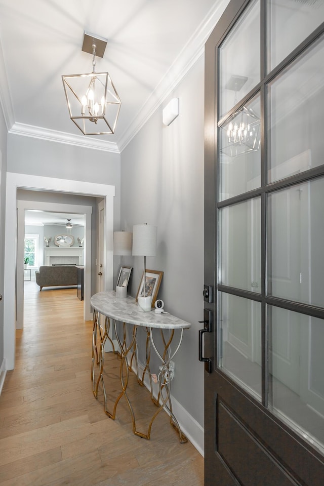 entryway with baseboards, light wood-style floors, a chandelier, and ornamental molding