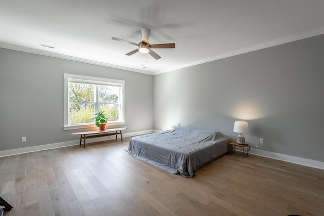 bedroom featuring baseboards, visible vents, wood finished floors, ceiling fan, and crown molding