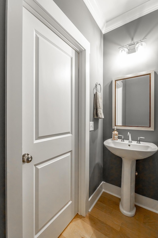 bathroom with baseboards, wood finished floors, and crown molding