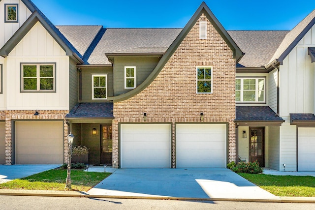 view of property featuring driveway, brick siding, and a garage