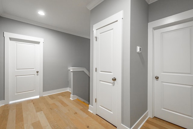corridor with baseboards, ornamental molding, an upstairs landing, and light wood-style flooring