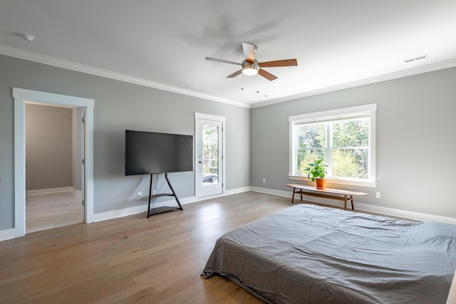 bedroom featuring wood finished floors, visible vents, crown molding, and multiple windows