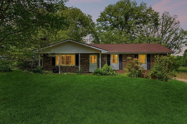 ranch-style home featuring brick siding and a yard