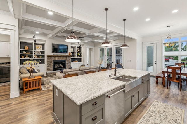 kitchen with a sink, pendant lighting, wood finished floors, gray cabinets, and dishwasher