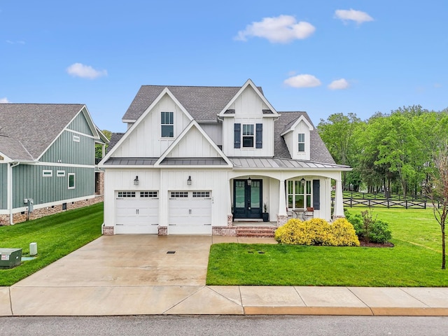 view of front of home featuring board and batten siding, a standing seam roof, driveway, a porch, and a front yard