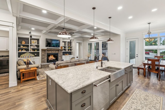 kitchen with gray cabinets, stainless steel dishwasher, wood finished floors, and a sink