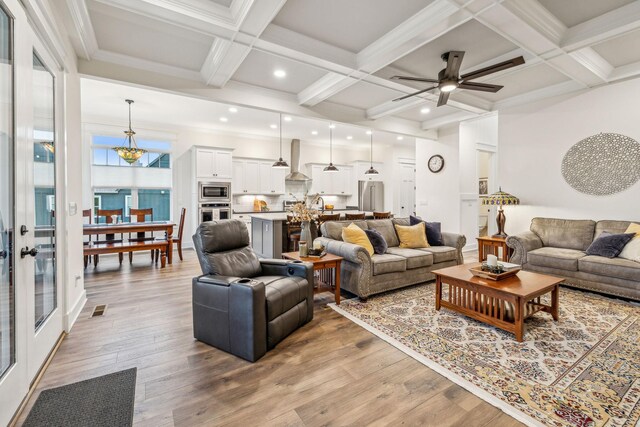living area with coffered ceiling, visible vents, a ceiling fan, beamed ceiling, and light wood-type flooring