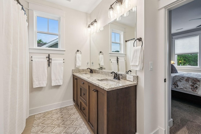 ensuite bathroom with plenty of natural light, baseboards, and a sink