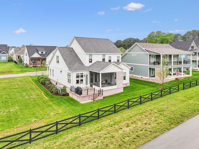 rear view of property with a patio area, a sunroom, roof with shingles, and a residential view