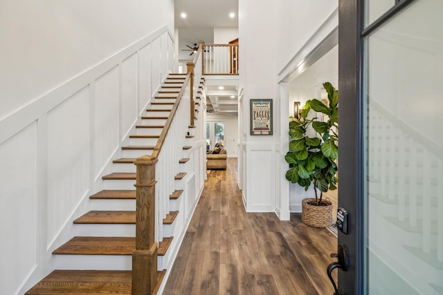 stairway featuring wood finished floors, recessed lighting, and a decorative wall