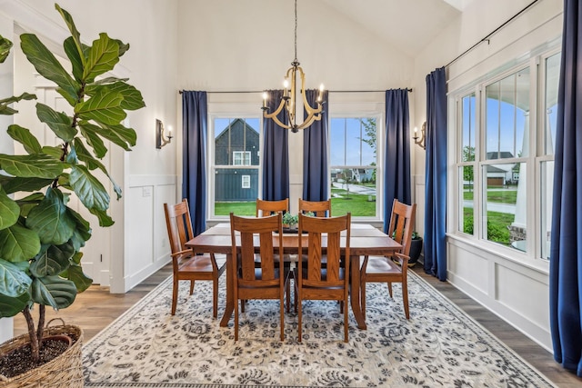 dining area featuring lofted ceiling, plenty of natural light, wood finished floors, and a notable chandelier