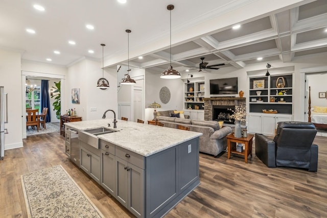 kitchen featuring a sink, ceiling fan with notable chandelier, gray cabinets, dishwasher, and a brick fireplace