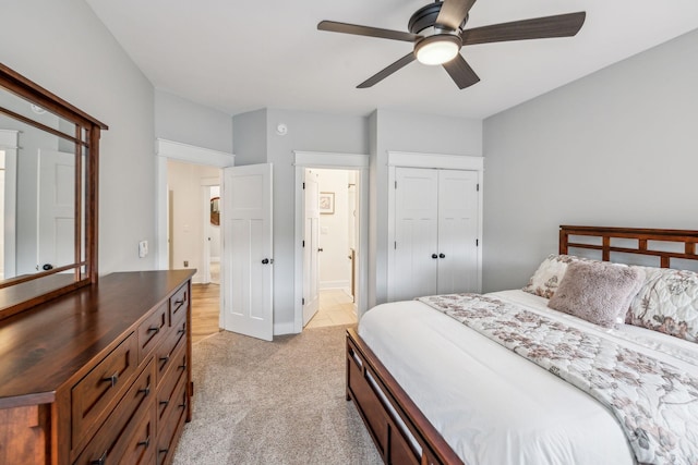 bedroom featuring a closet, a ceiling fan, light carpet, and ensuite bathroom