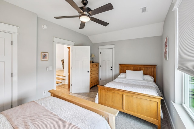carpeted bedroom featuring ceiling fan, vaulted ceiling, visible vents, and baseboards