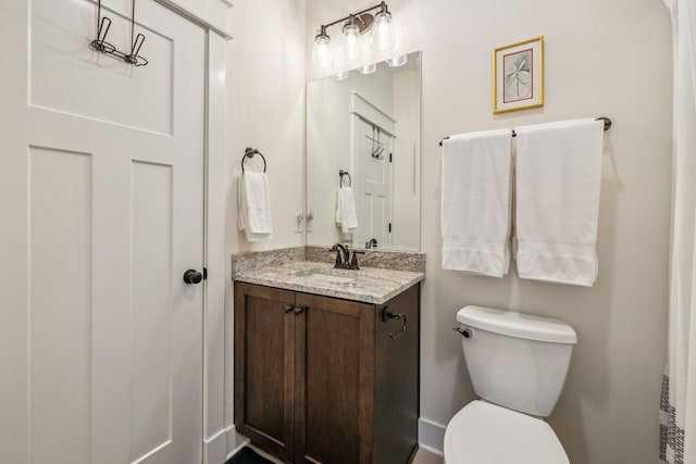 bathroom featuring baseboards, toilet, and vanity