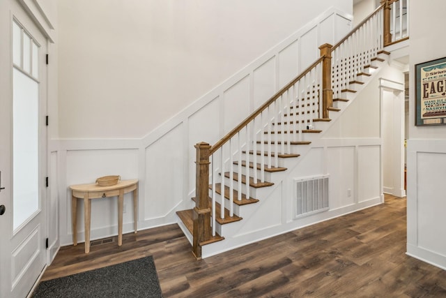 stairway featuring wainscoting, wood finished floors, visible vents, and a decorative wall