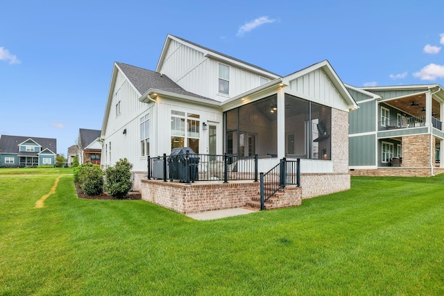 back of property with board and batten siding, a yard, a ceiling fan, and a sunroom