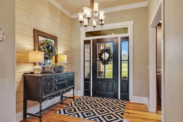 entryway with a chandelier, wood finished floors, wood walls, and baseboards