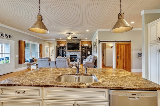kitchen with dishwasher, a large fireplace, open floor plan, and a sink