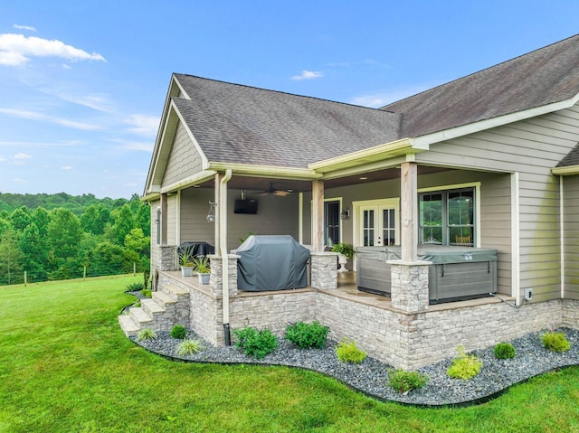 exterior space with french doors, a ceiling fan, a shingled roof, a yard, and area for grilling