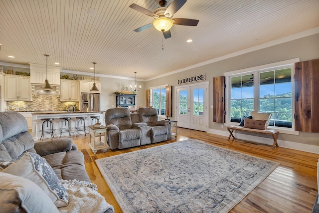 living room with crown molding, a ceiling fan, light wood finished floors, and a healthy amount of sunlight
