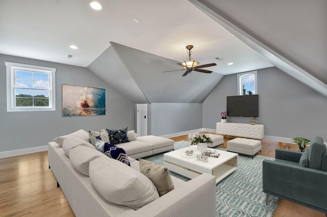 living area with baseboards, a ceiling fan, light wood-style flooring, and lofted ceiling