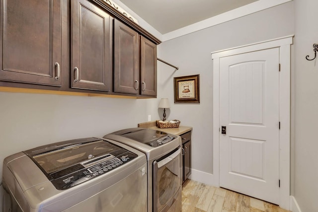 laundry area with cabinet space, light wood-style floors, baseboards, and washer and clothes dryer
