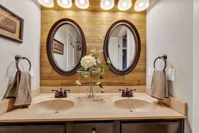 bathroom with wooden walls, double vanity, and a sink