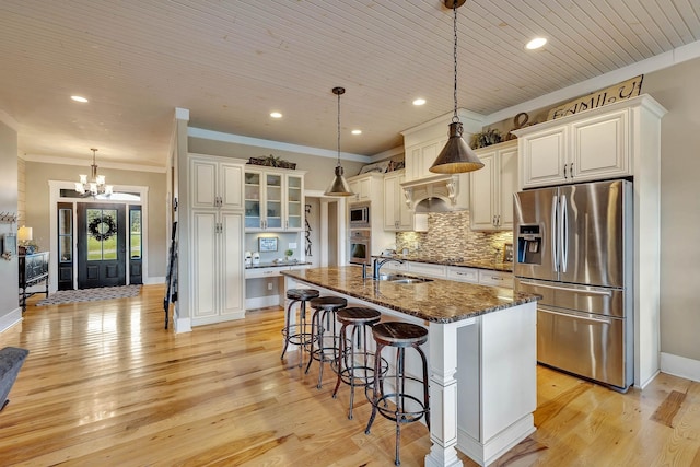 kitchen with stainless steel appliances, a sink, an inviting chandelier, crown molding, and a breakfast bar